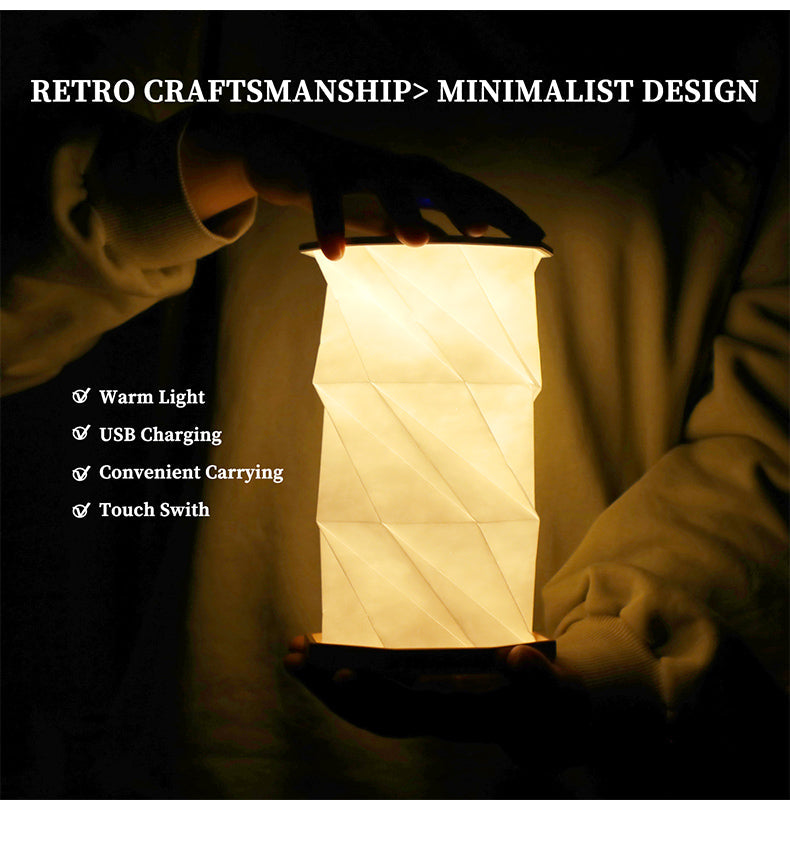 White collapsible lantern lamp with geometric origami-style fold pattern illuminated in warm light
