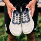 OluKai Men's Kialoa sneaker in Tapa cream mesh with Trench Blue overlay held by hands