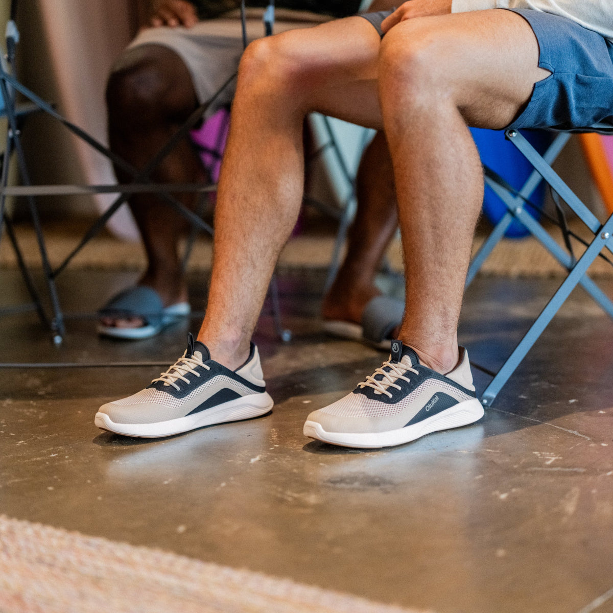 OluKai Kialoa men's sneaker in Tapa tan and Trench Blue navy colorway on feet