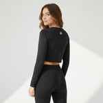 Woman wearing black long-sleeve crop top and matching black high-waist leggings, rear view