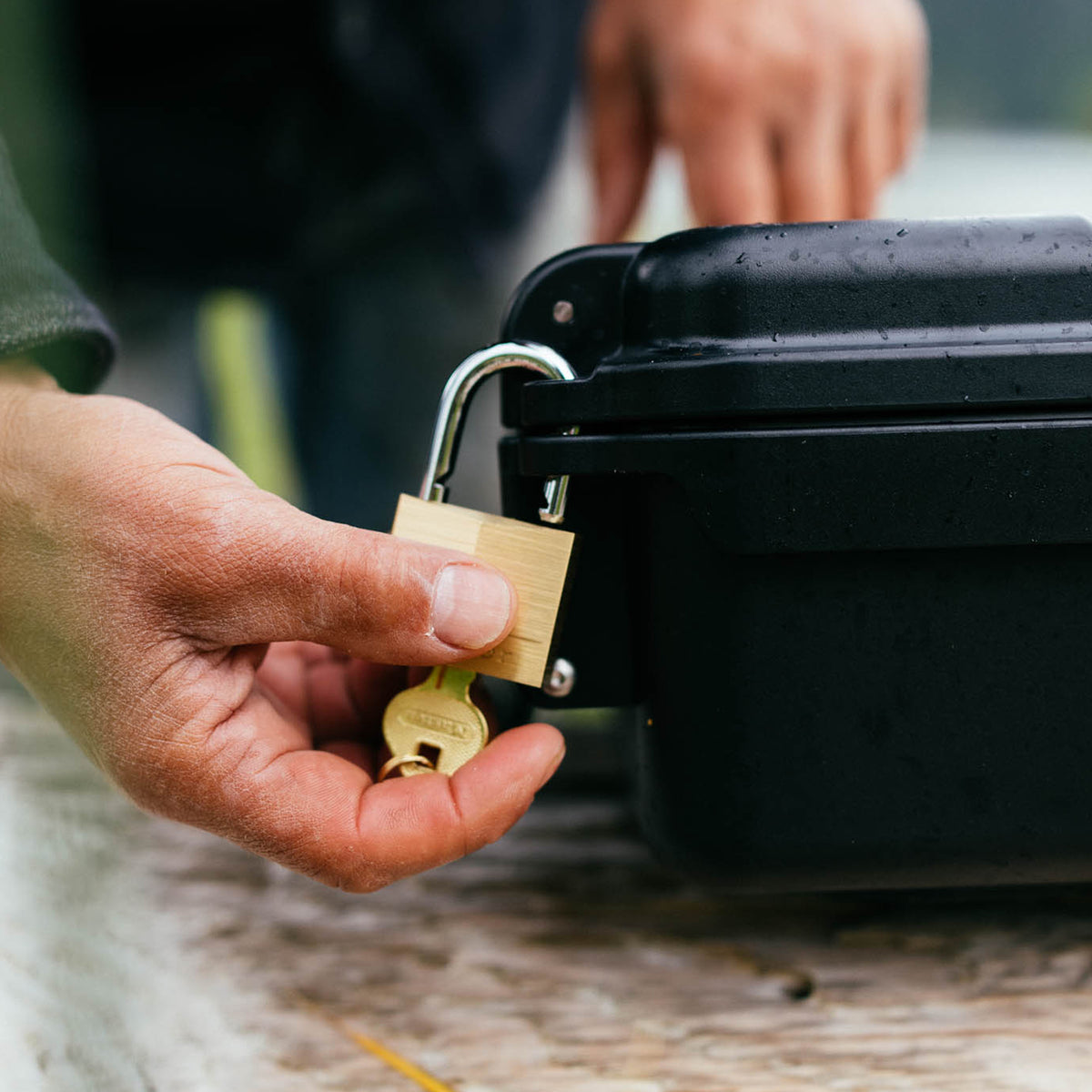 YETI GoBox 10 in black being secured with a brass padlock and key outdoors