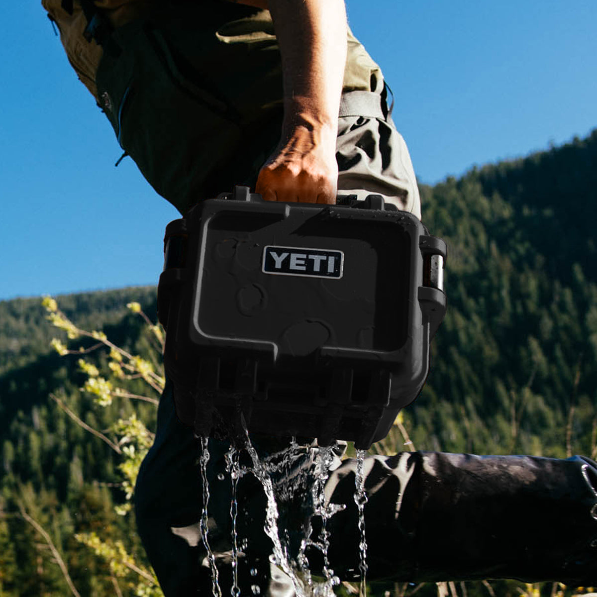 YETI Loadout GoBox 8 in black being lifted from water in outdoor mountain setting