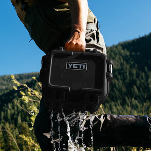 YETI Loadout GoBox 8 in black being lifted from water in outdoor mountain setting