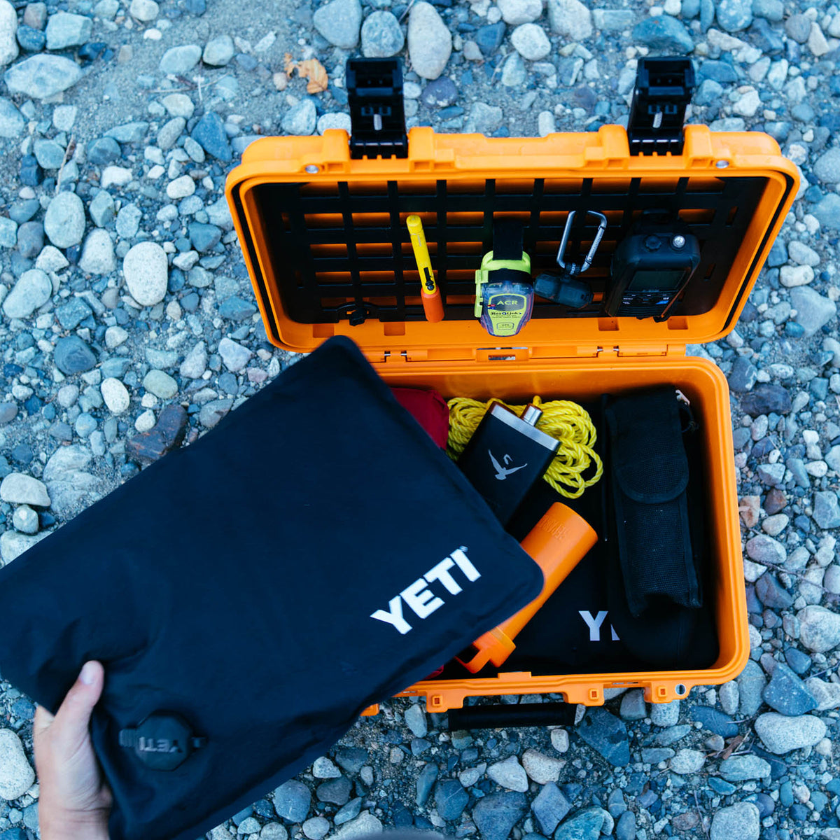 YETI Loadout GoBox KOR protective black inserts being removed from orange rugged case on rocky ground