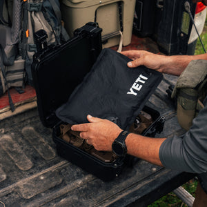 Person loading YETI Loadout GoBox with black KOR protective insert on truck bed