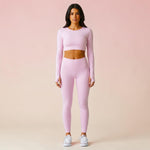 Woman wearing light rose pink high-waist leggings and matching long-sleeve crop top with white sneakers