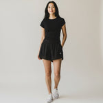 Woman wearing black Grace in Motion shorts with black tee and white sneakers