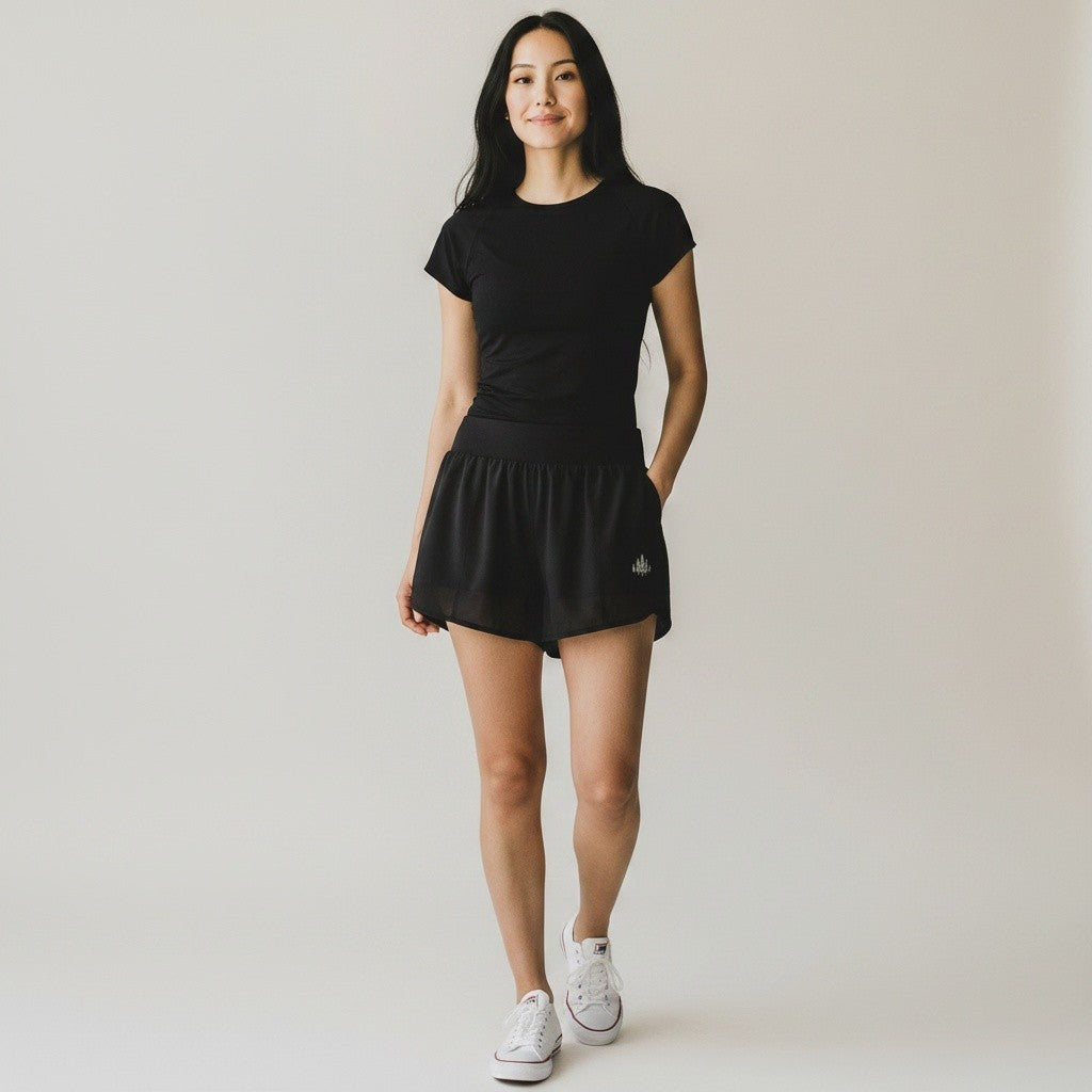 Woman wearing black Grace in Motion shorts with black tee and white sneakers