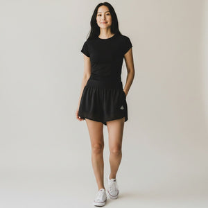 Woman wearing black Grace in Motion shorts with black tee and white sneakers