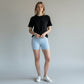 Mercifully Made Short in sky blue worn by model with black t-shirt and white sneakers