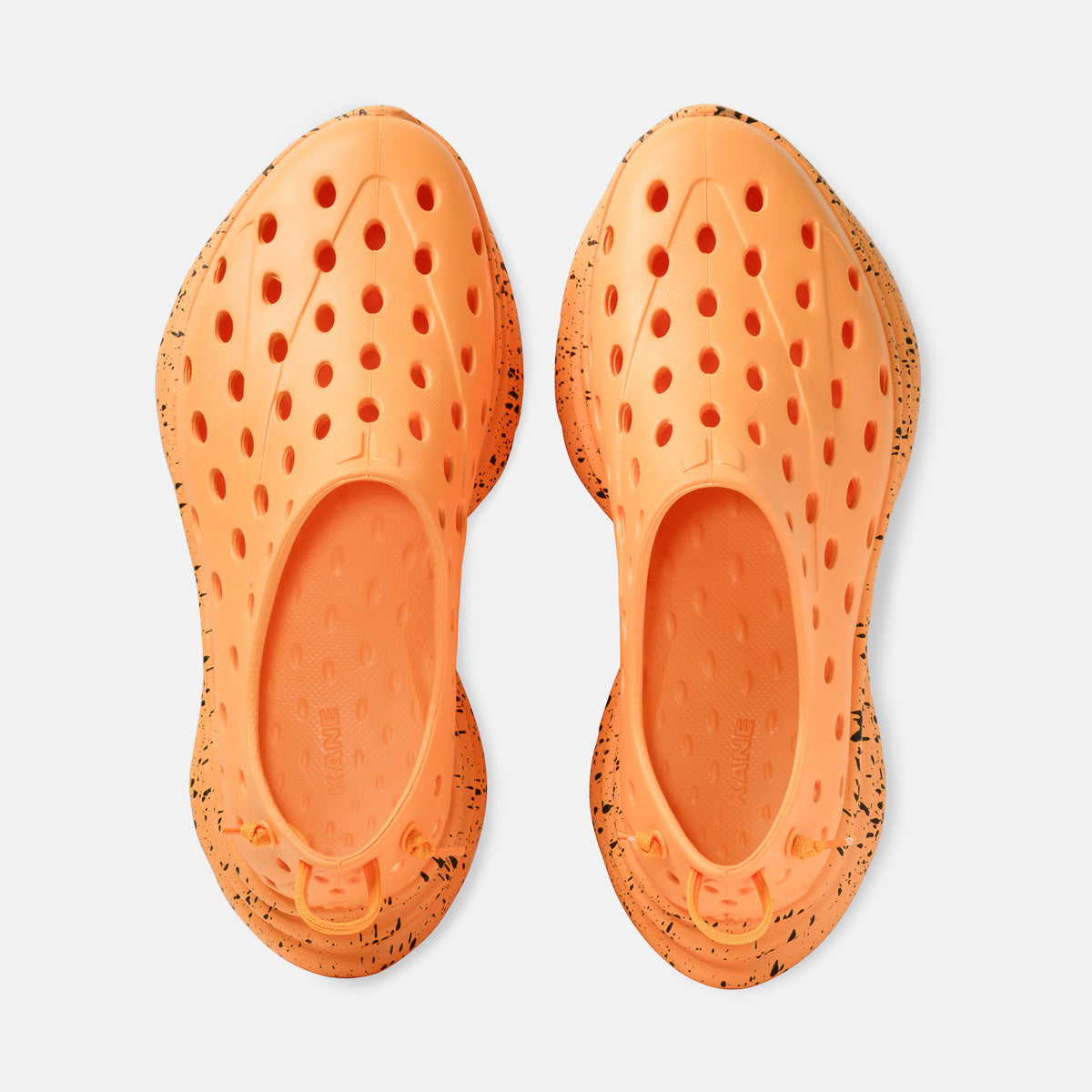 Kane Revive shoes in electric orange with black speckle midsole, top-down view showing ventilation holes