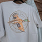 Coastal Cotton Mallard Tradewind Tee back view showing flying duck circular graphic on light blue-grey shirt
