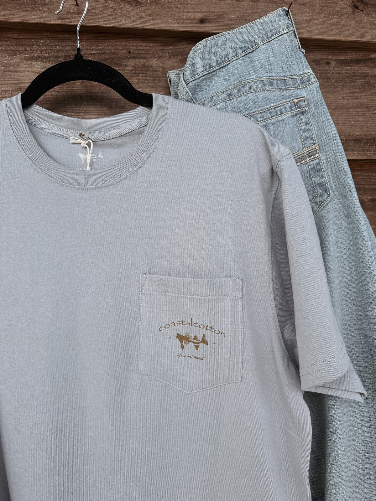 Coastal Cotton Mallard Tradewind Tee in light blue-gray with chest pocket logo, styled with jeans
