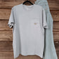 Coastal Cotton Mallard Tradewind pocket tee in light gray-blue hanging on wooden wall