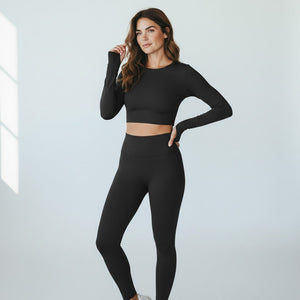 Woman wearing Mercifully Made black high-waist leggings with matching long-sleeve crop top