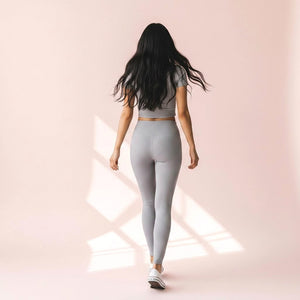 Woman walking away wearing Mercifully Made Legging in Pebble Gray with matching crop top