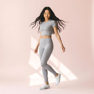 Woman wearing Mercifully Made Legging in Pebble Gray with matching crop top and white sneakers