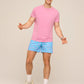 Man wearing pink t-shirt and dusty blue patterned swim trunks with white sneakers