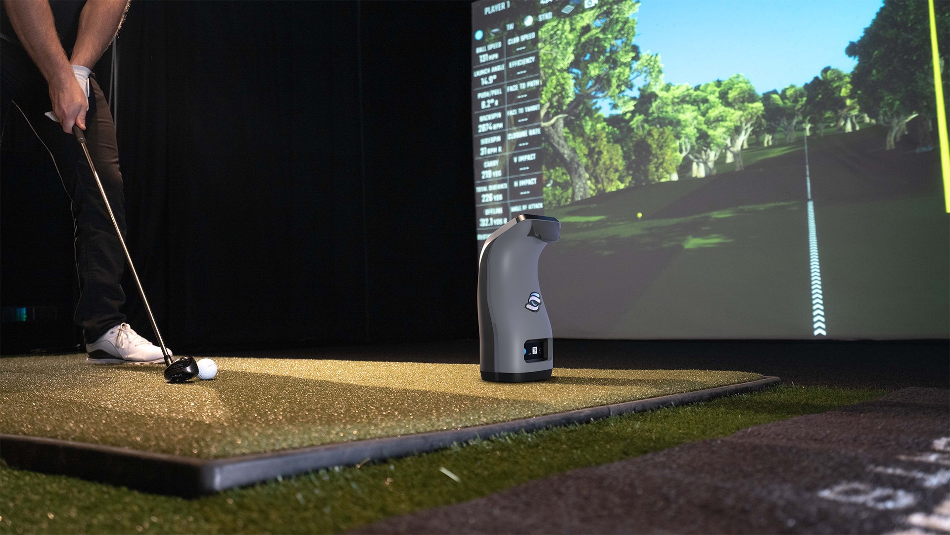 Foresight QC3 launch monitor on golf mat beside player in indoor simulator bay