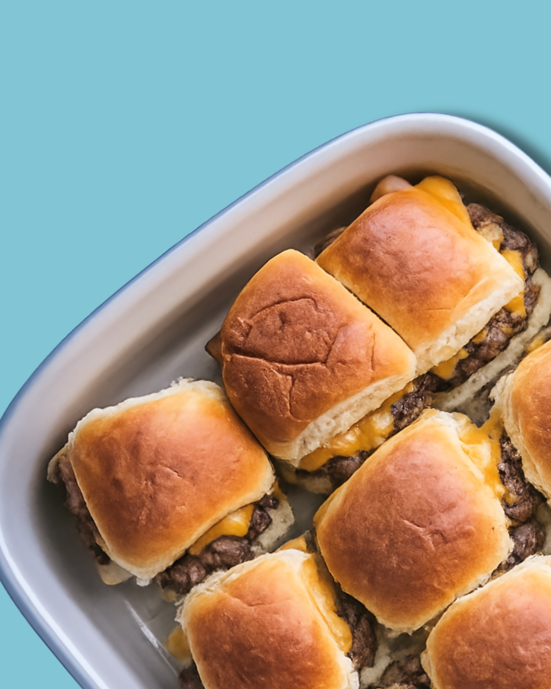 Six cheeseburger sliders with golden brioche buns and melted cheese in white serving dish