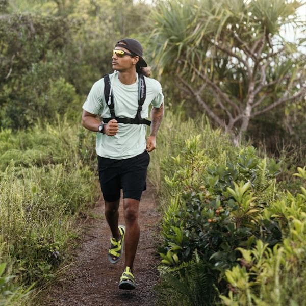 Man trail running wearing black Teva Aventrail shoes with bright yellow accent details