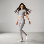 Woman wearing gray crop top and matching high-waist leggings with white Converse sneakers