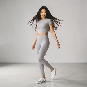 Woman wearing gray crop top and matching high-waist leggings with white Converse sneakers